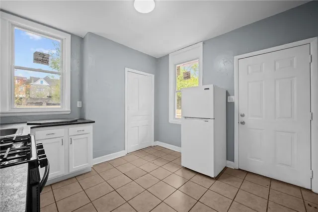 a kitchen with white cabinets and refrigerator