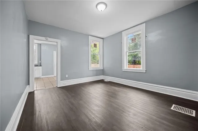 an empty room with wooden floor and windows