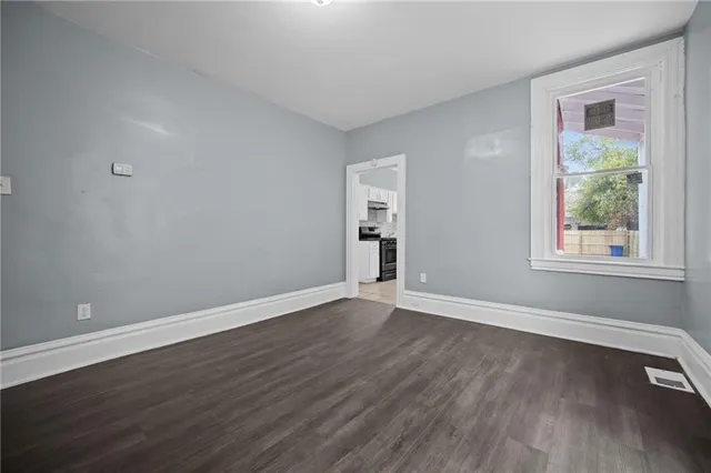 a view of an empty room with wooden floor and a window