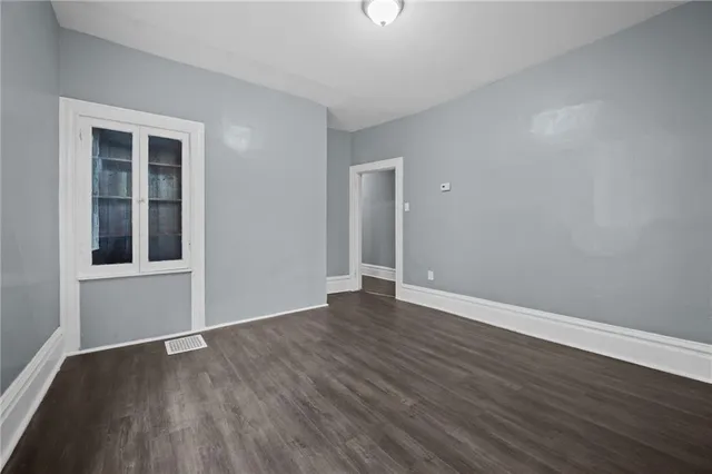 a view of an empty room with wooden floor and windows