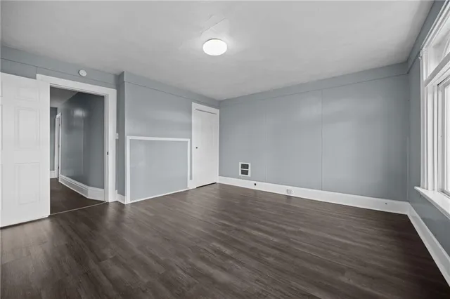 an empty room with wooden floor & windows in it