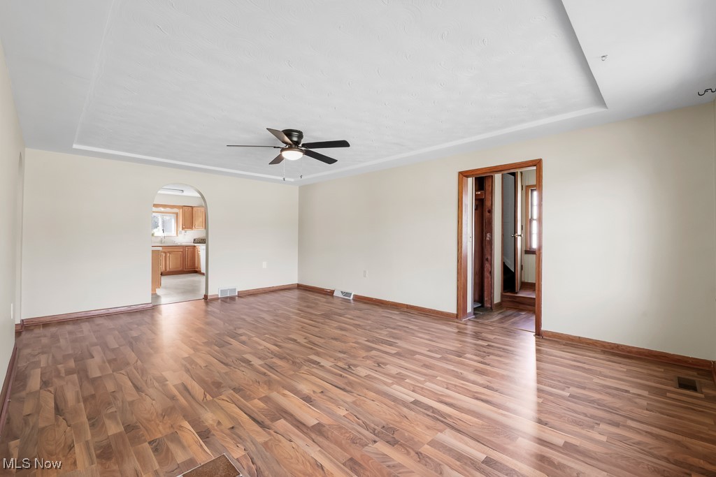 1702 Far View Road Akron, OH 44312 - Photo 5 of 49 Unfurnished living room with a tray ceiling, light wood finished floors, arched walkways, and ceiling fan