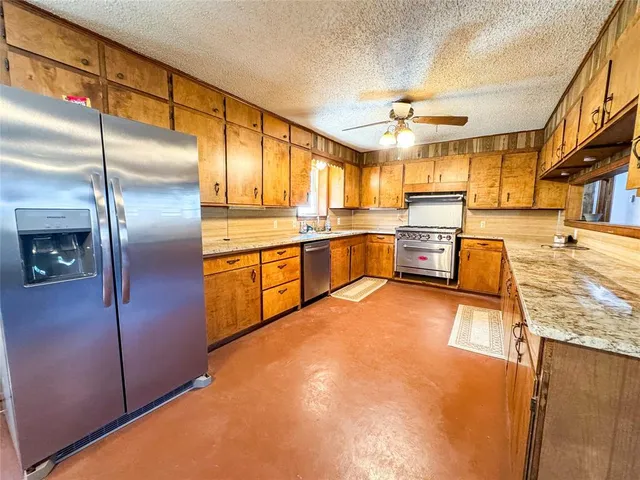 a kitchen with stainless steel appliances granite countertop a sink refrigerator stove and microwave