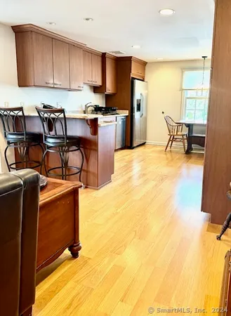 a open kitchen with stainless steel appliances granite countertop a sink a stove top oven a chimney and a dining table