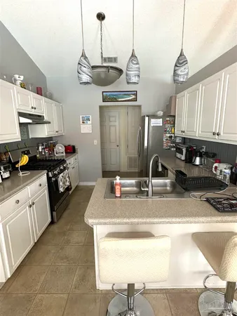 a kitchen with kitchen island granite countertop a sink a stove and cabinets
