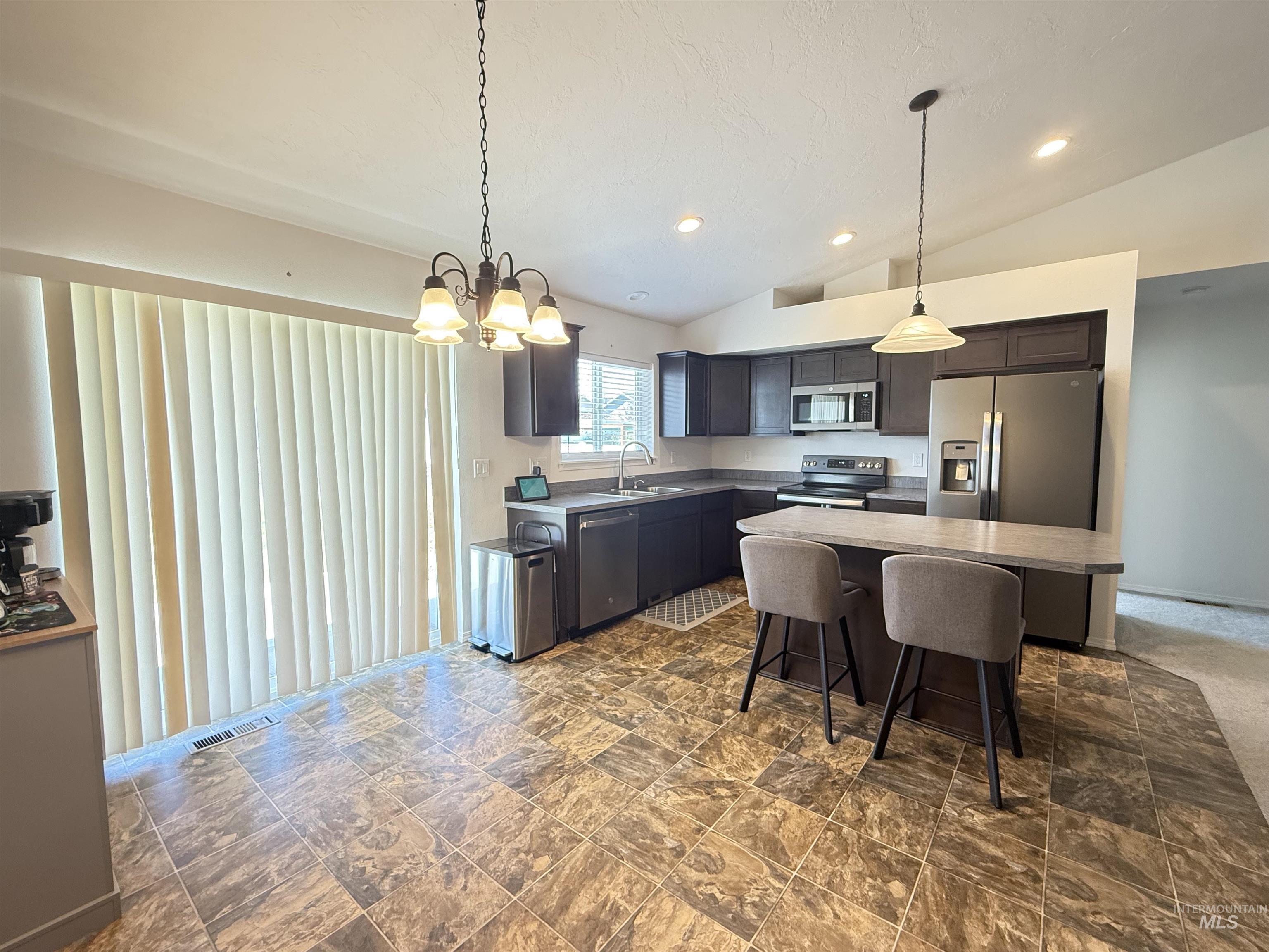 1556 Frontier Drive Lewiston, ID 83501 - Photo 10 of 23 Kitchen featuring dark wood cabinetry, stainless steel appliances, and a central island with countertop seating