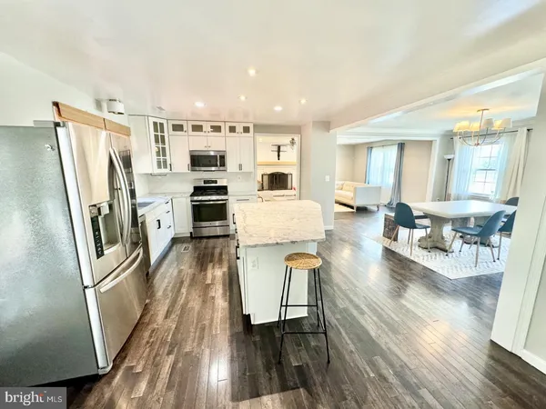 a living room with stainless steel appliances furniture and a wooden floor