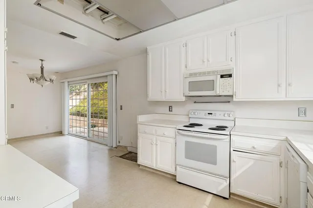 a kitchen with white cabinets and white appliances