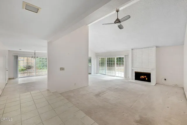 an empty room with windows and fireplace