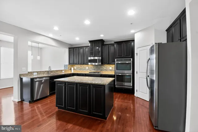 a kitchen with stainless steel appliances granite countertop a stove refrigerator and a sink