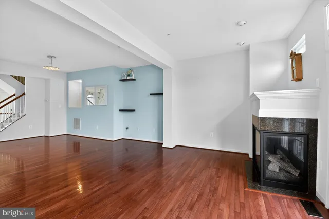 an empty room with wooden floor fireplace and windows
