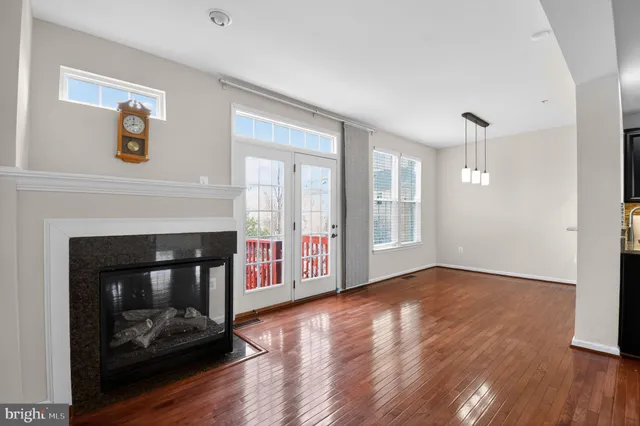 a view of an empty room with wooden floor fireplace and a window
