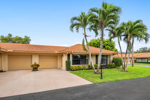 a front view of house with small garden and palm tree