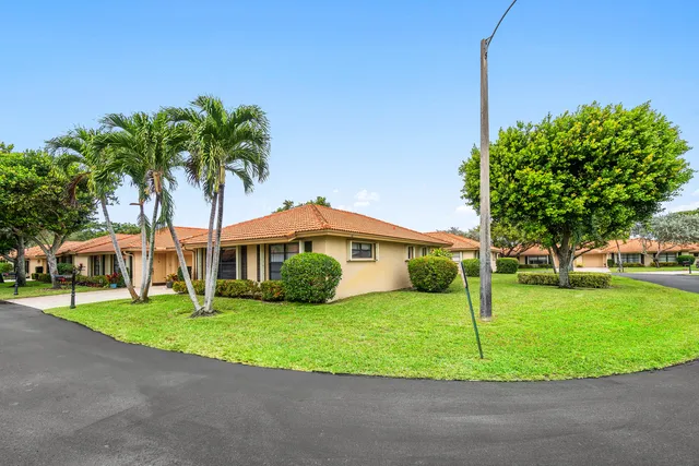 a front view of a house with a yard and palm trees