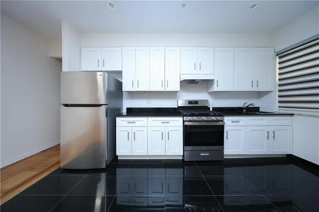 a kitchen with a refrigerator and white cabinets