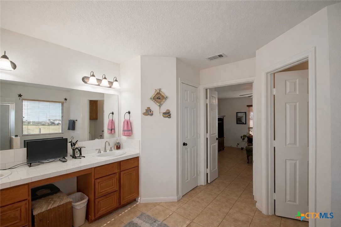 9439 Jeske Road Needville, TX 77461 - Photo 25 of 46 a en suite bathroom with a double vanity sink a mirror and a shower