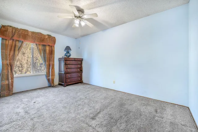an empty room with windows and ceiling fan