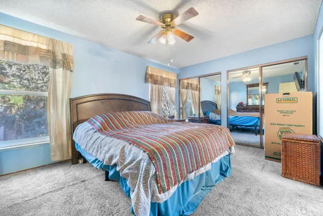 a bedroom with a bed and a large window with the outer view