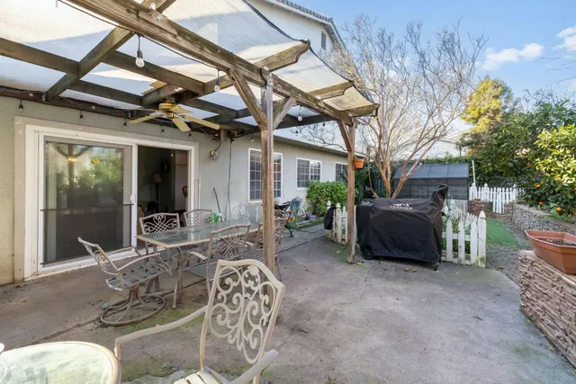 a view of a patio with table and chairs potted plants and large tree