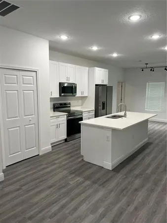a large kitchen with kitchen island a white counter top space stainless steel appliances and cabinets