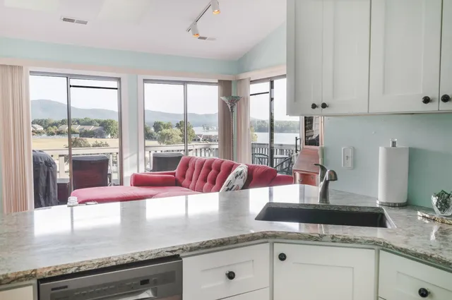 a kitchen with granite countertop a stove a sink and white cabinets