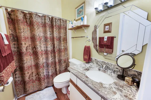 a bathroom with a granite countertop toilet sink and mirror