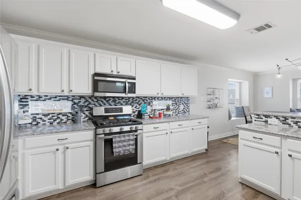 a kitchen with white cabinets and appliances