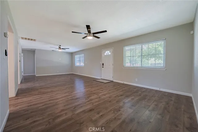 a view of empty room with wooden floor and ceiling fan