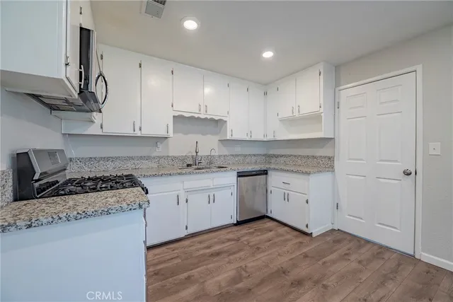 a kitchen with granite countertop a sink stainless steel appliances and cabinets