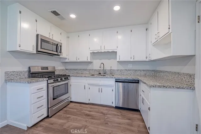 a kitchen with granite countertop cabinets stainless steel appliances and a sink