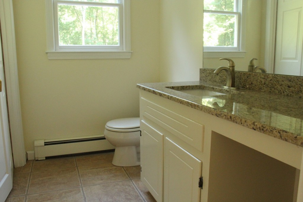 18 Line Road Westford, MA 01886 - Photo 4 of 12 a bathroom with a granite countertop toilet a sink a mirror and a window