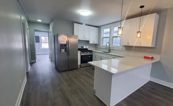 a kitchen with stainless steel appliances granite countertop a refrigerator a sink a stove and wooden floors