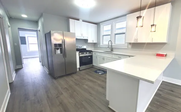 a kitchen with stainless steel appliances a refrigerator a sink dishwasher a stove and white countertops with wooden floor