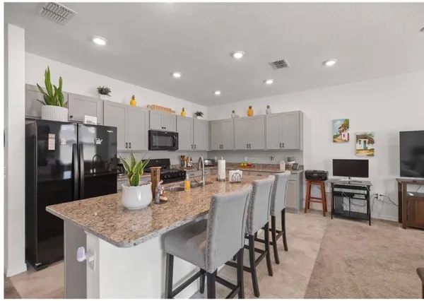 a kitchen with stainless steel appliances granite countertop a stove top oven a sink a dining table and chairs