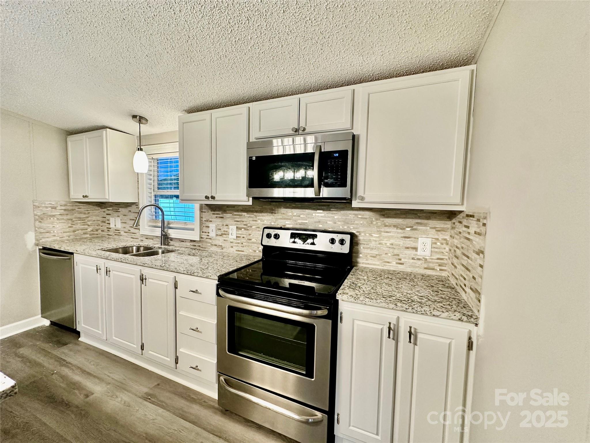 980 Olde Creek Trail Concord, NC 28025 - Photo 13 of 26 a kitchen with granite countertop a stove and a microwave