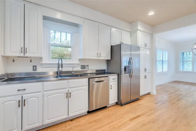 a kitchen with stainless steel appliances granite countertop a refrigerator sink and white cabinets
