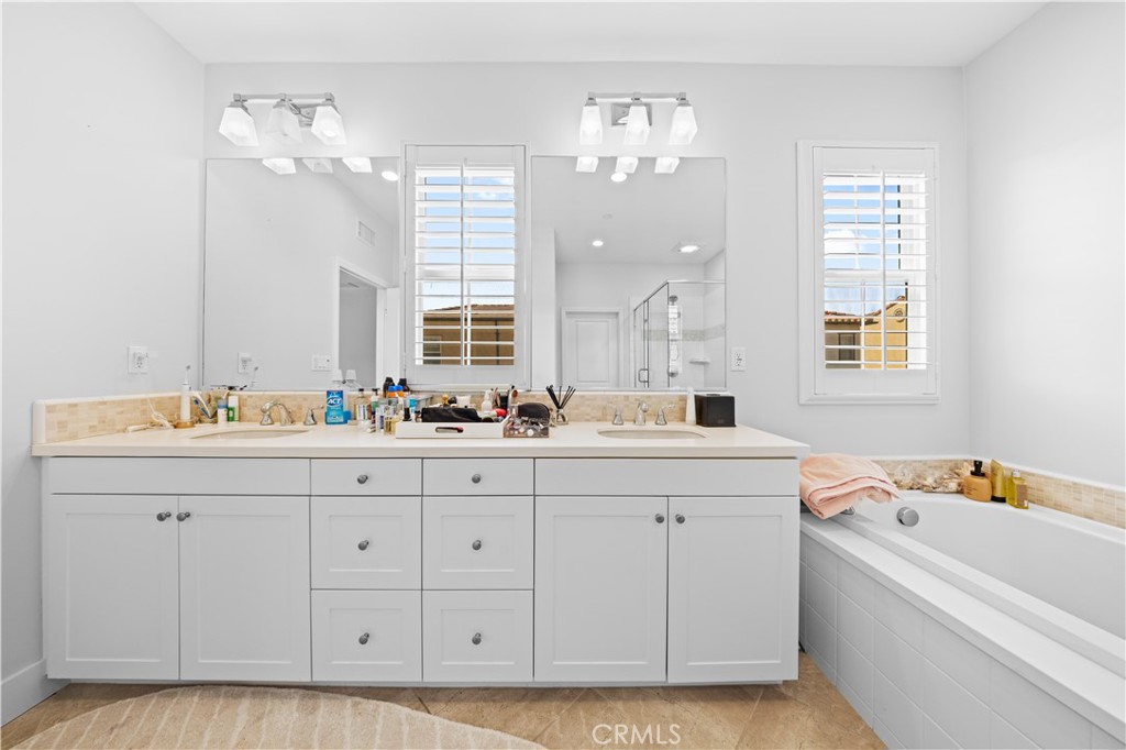 63 Birmingham Irvine, CA 92620 - Photo 19 of 28 a bathroom with a double vanity sink a mirror a bathtub and next to a window