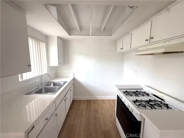 a kitchen with white cabinets stove and sink