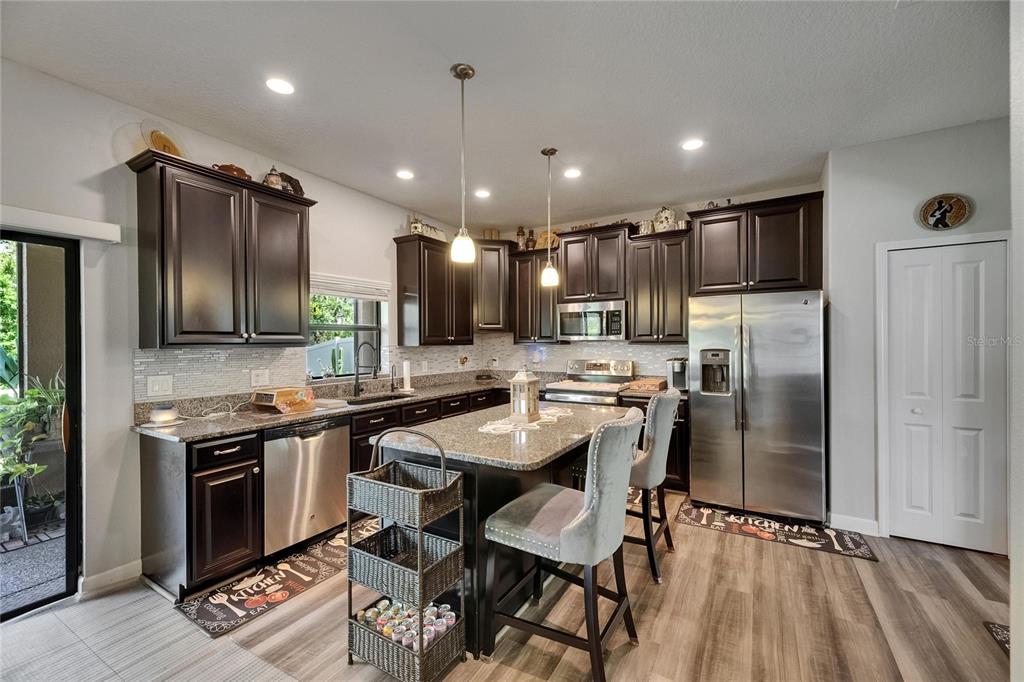 5057 Ivory Stone Drive Wimauma, FL 33598 - Photo 12 of 46 a kitchen with stainless steel appliances granite countertop a stove refrigerator and a sink