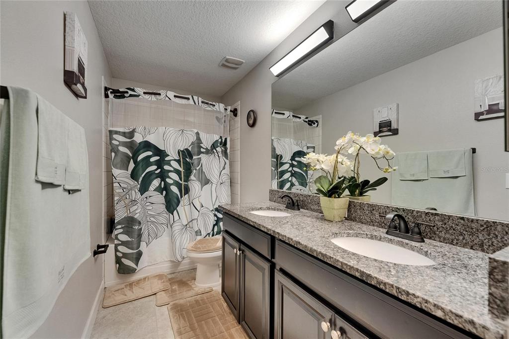 5057 Ivory Stone Drive Wimauma, FL 33598 - Photo 34 of 46 a bathroom with a granite countertop sink a mirror and shower