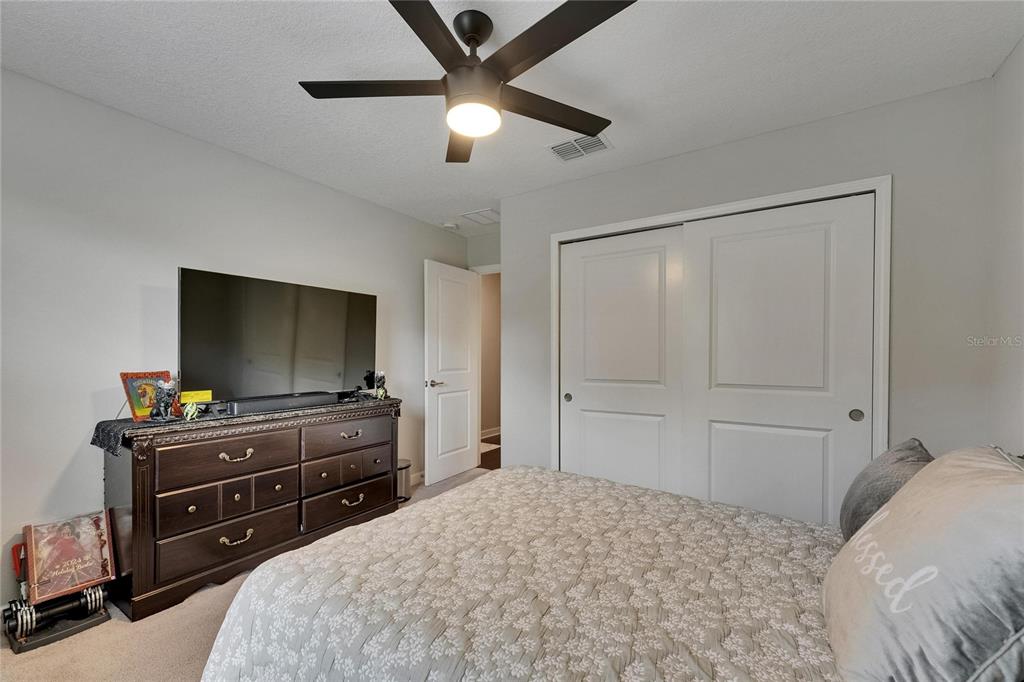 5057 Ivory Stone Drive Wimauma, FL 33598 - Photo 38 of 46 a bedroom with a bed and a flat screen tv