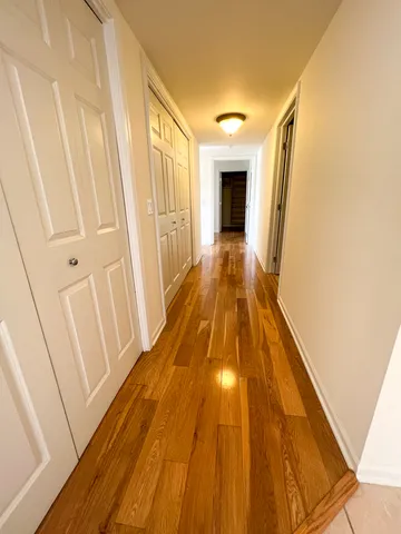 a view of a hallway with wooden floor and staircase