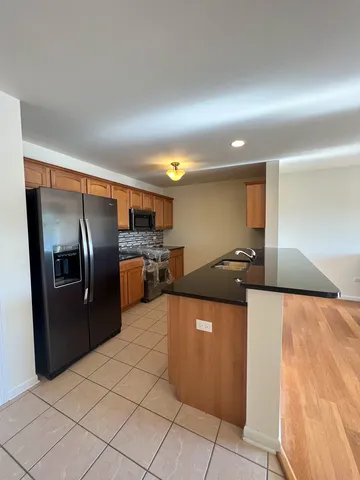 a kitchen with stainless steel appliances kitchen island granite countertop a refrigerator and a sink