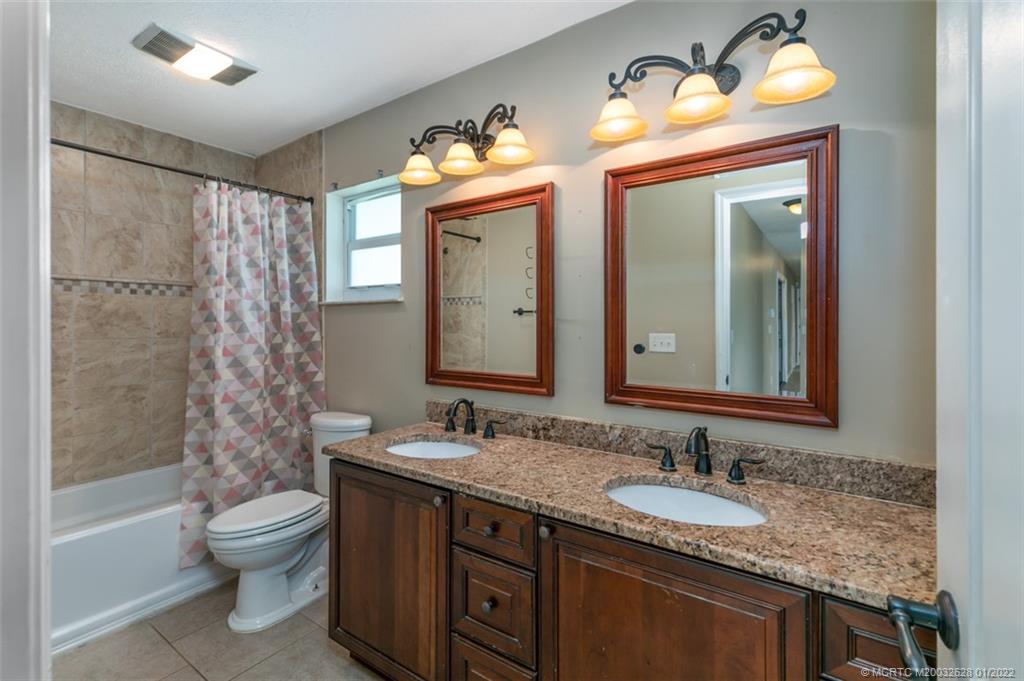2891 Southeast Farley Road Port St. Lucie, FL 34952 - Photo 21 of 53 a bathroom with a granite countertop sink toilet a mirror and shower