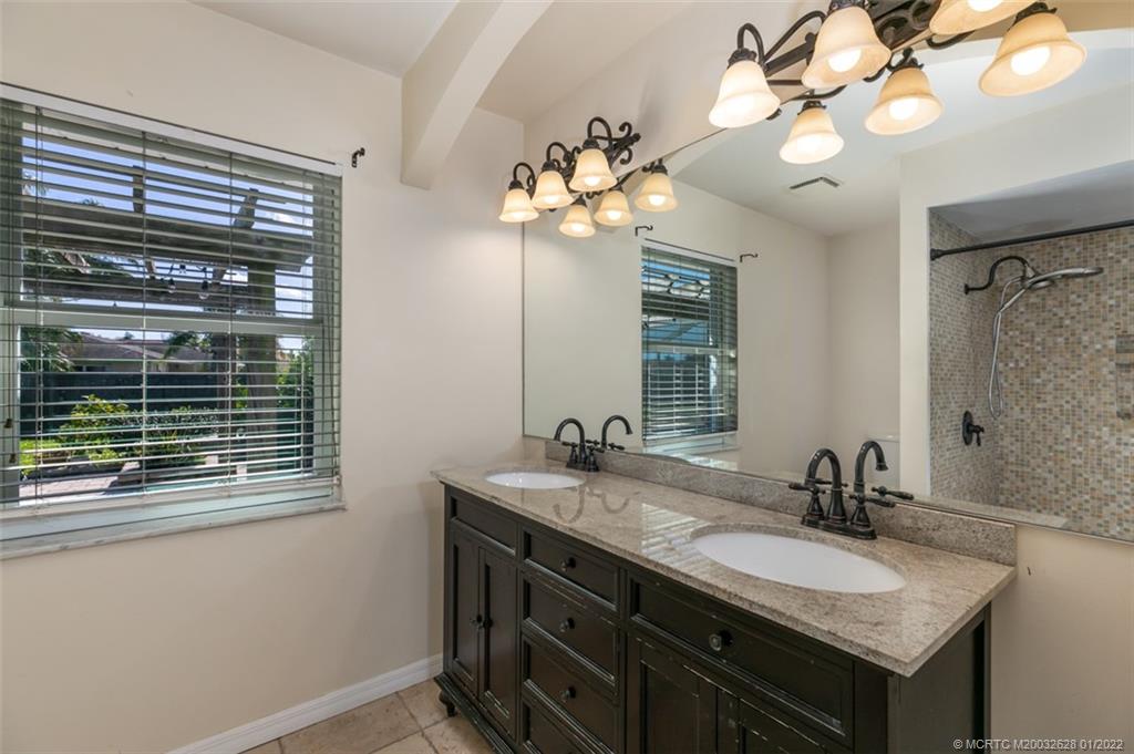 2891 Southeast Farley Road Port St. Lucie, FL 34952 - Photo 27 of 53 a bathroom with a granite countertop sink a large mirror and a light fixture