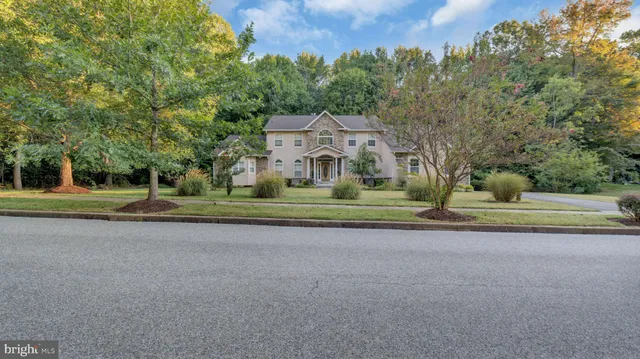 a front view of a house with a big yard and palm trees
