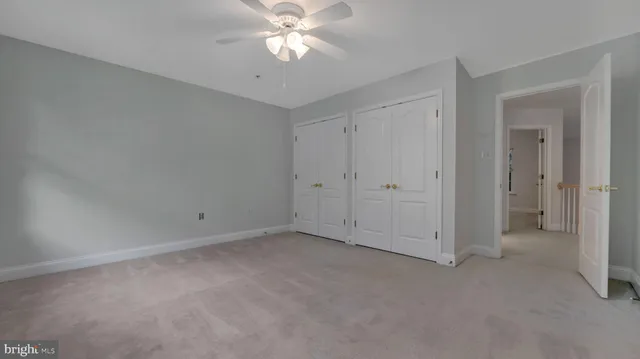 an empty room with a chandelier fan and windows