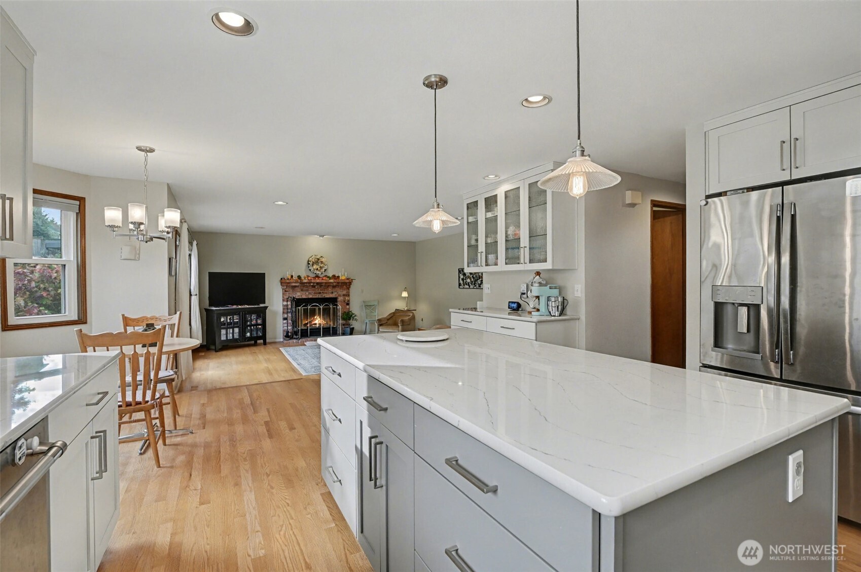 15823 Southeast 182nd Place Renton, WA 98058 - Photo 15 of 30 a large kitchen with kitchen island a refrigerator a stove a sink a dining table and chairs with wooden floor