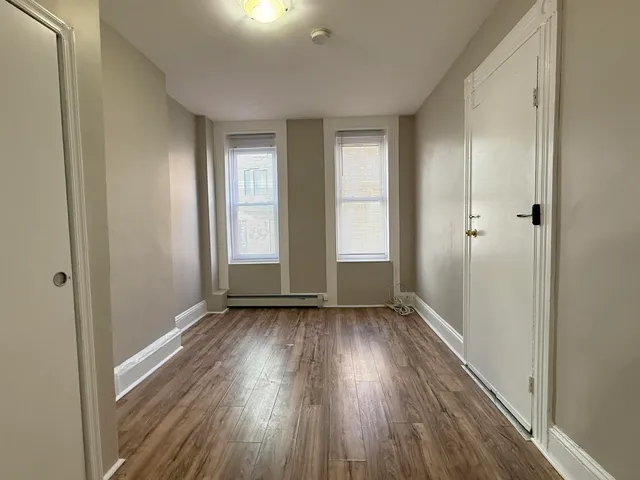 a view of an empty room with glass door and wooden floor