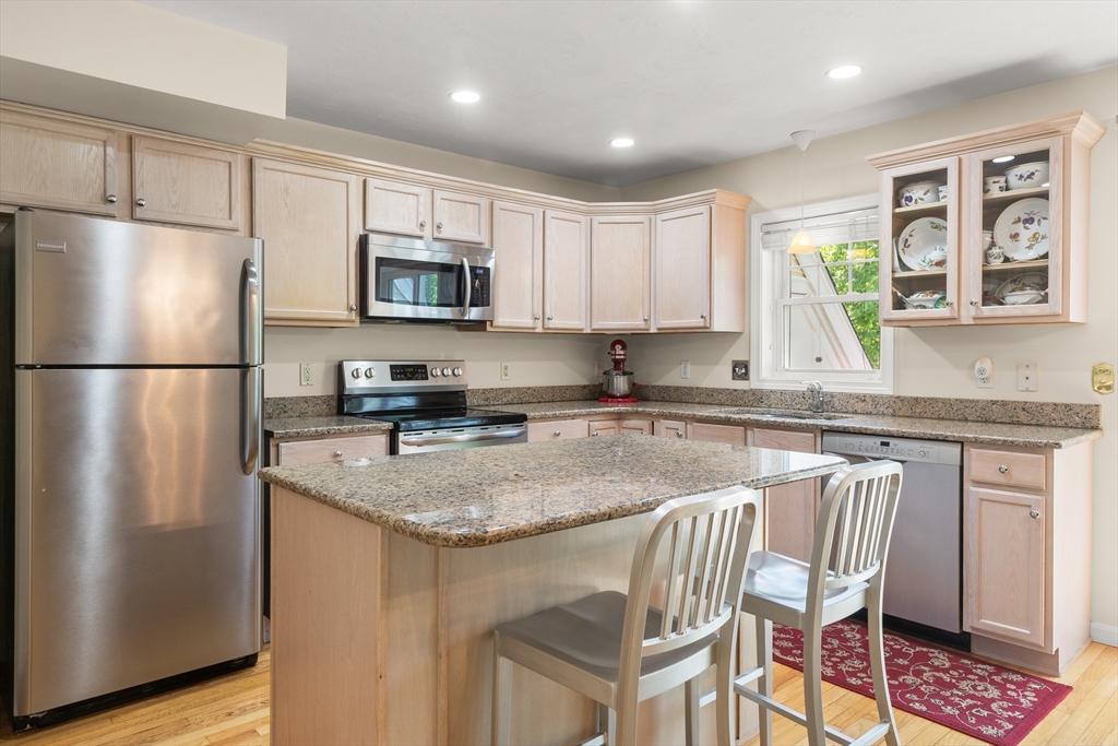 35 Collins Street, Unit 87 Danvers, MA 01923 - Photo 2 of 28 a kitchen with stainless steel appliances granite countertop a refrigerator a stove a sink a dining table and chairs with wooden floor